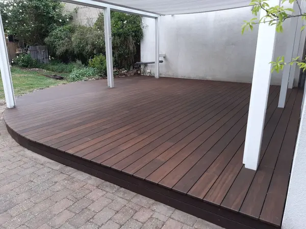 Überdachte Holzterrasse mit dunkel geölten Dielen und abgerundeter Kante
